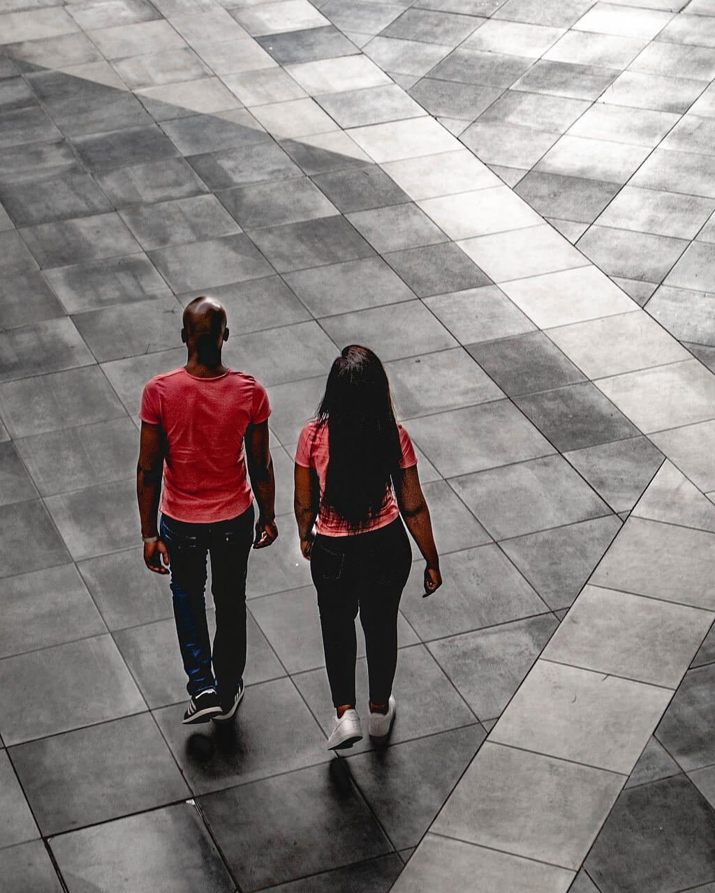 Two people walking on a tiled floor holding hands